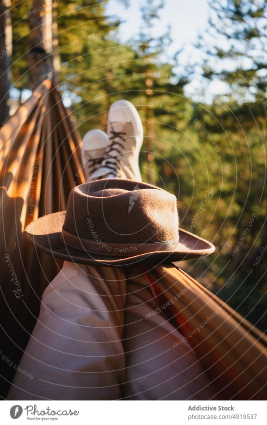Unrecognizable traveler lying in hammock hat forest nature recreation woods leisure chill tourism adventure trip tourist leg pastime headwear tree summer plant