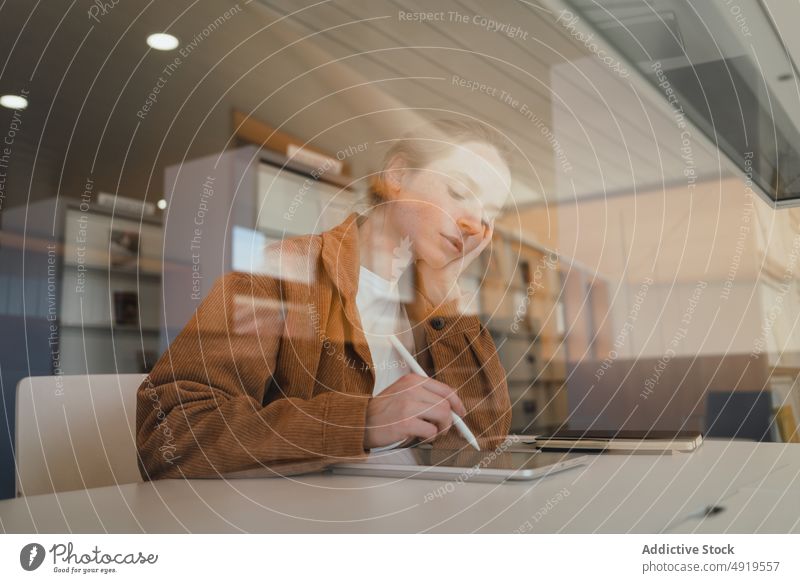 Young woman using tablet behind glass in library student education homework study university project female young browsing gadget learn college device research