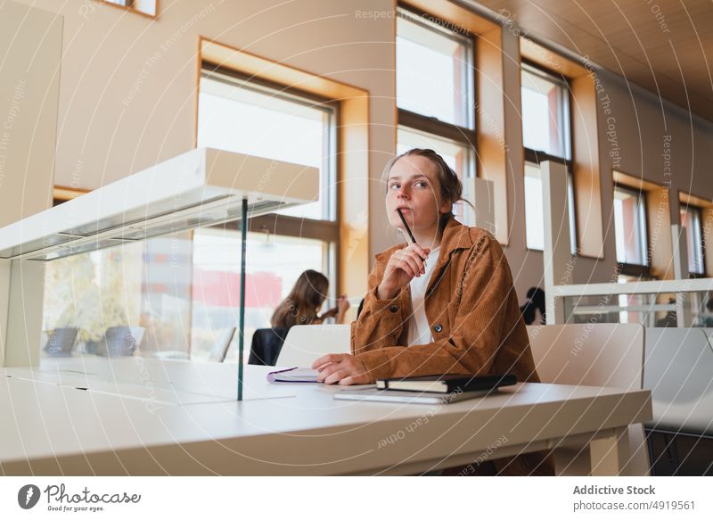 Thoughtful woman studying in library student think homework thoughtful university assignment education female young pensive learn college exam preparation