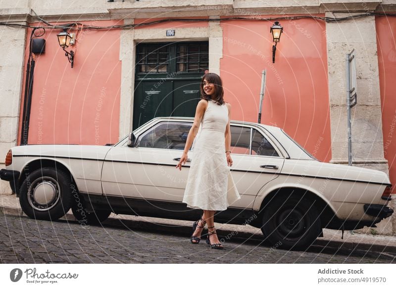 Content woman near retro car in city street style old timer vintage dress parked building attire positive glad pleasant optimist content shabby smile weathered