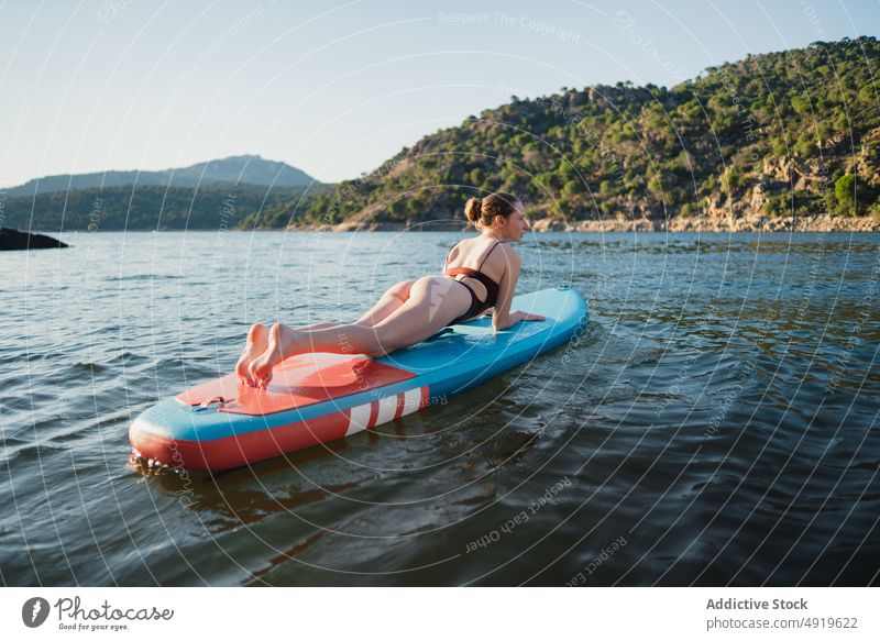 Woman lying on paddleboard in lake woman leisure hobby water rest nature wellbeing swimwear summer sup board slender shore float relax forest vacation coast
