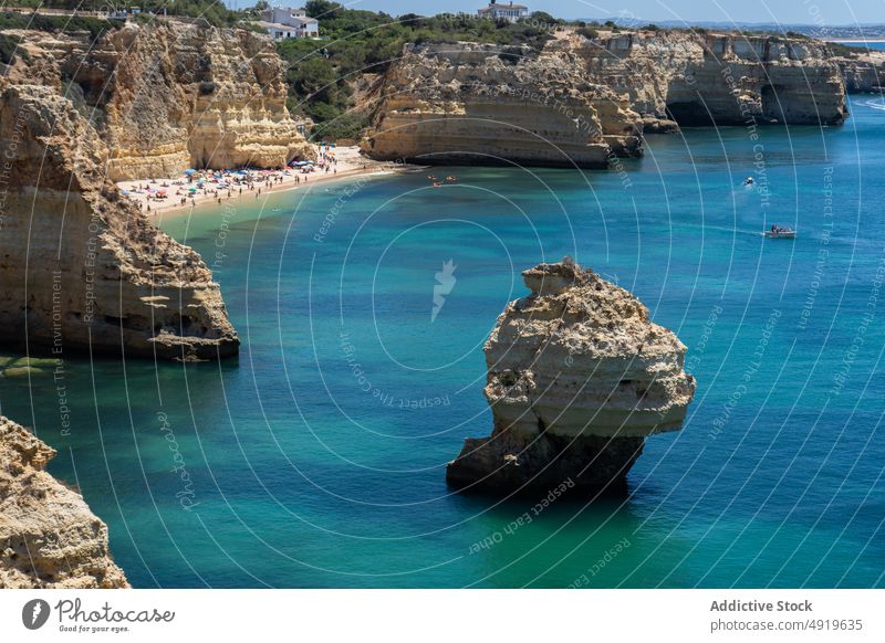 People on a boat and kayak near rough rocks in between ocean nature landscape algarve aerial view seascape horizon blue sky geology formation high endless