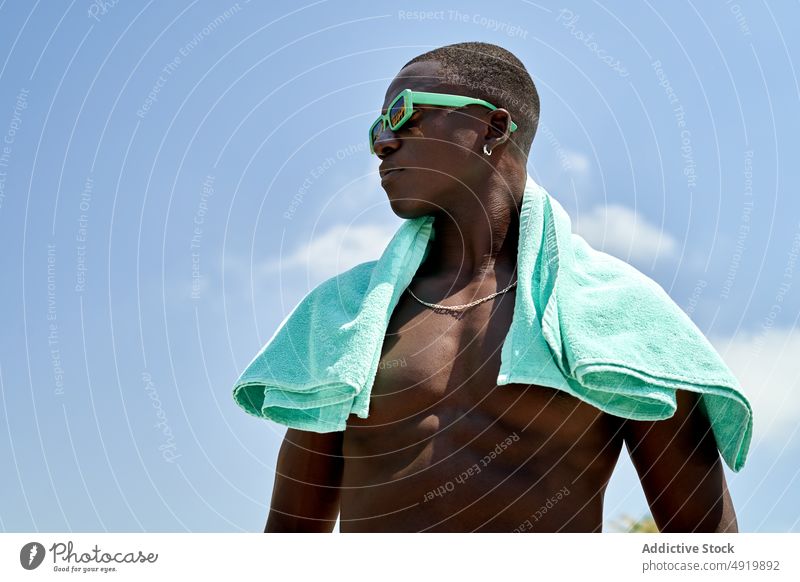Shirtless black man with towel naked torso rest recreation pastime tropical nature sunglasses appearance leisure african american shirtless ethnic blue sky