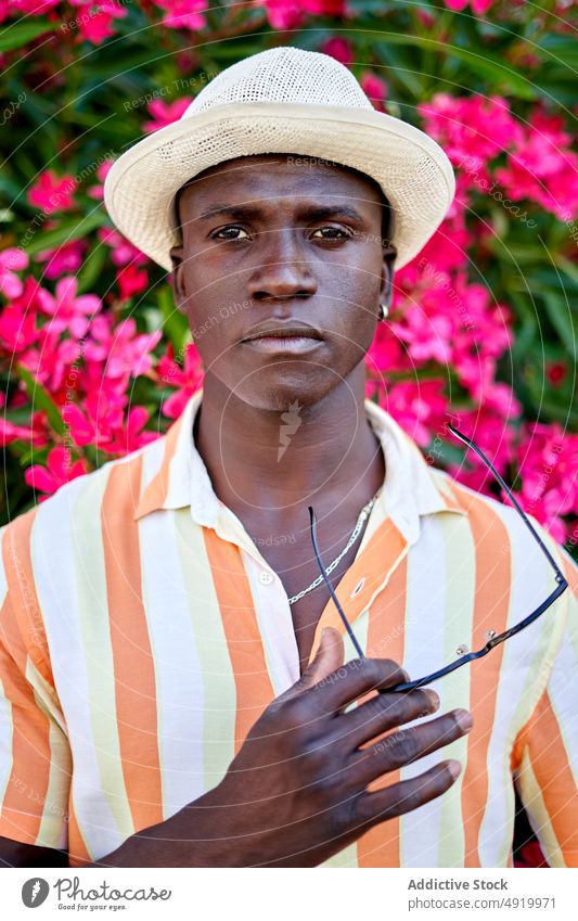 Serious black man near blooming bush street flower plant appearance city floral attire style african american ethnic summer male guy town entrepreneur modern