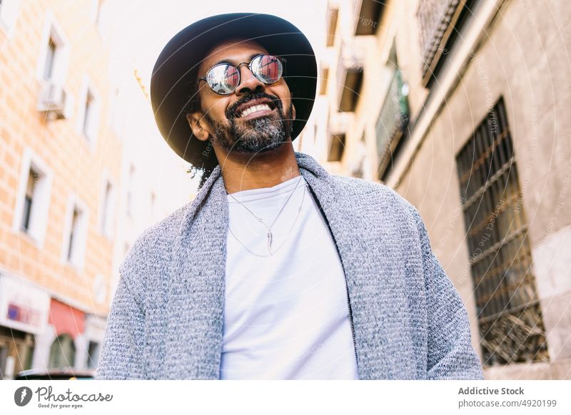Stylish Hispanic man on city street street style urban daytime outfit rest appearance male hispanic ethnic adult modern trendy sunglasses hat sunlight
