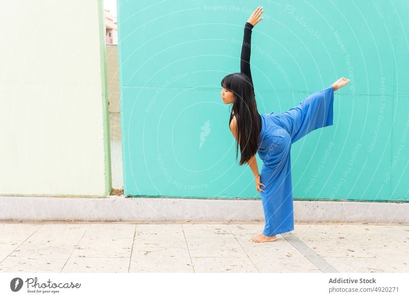 Asian woman dancing on pavement dance street grace wall arm raised lunge urban female young asian ethnic energy talent barefoot long hair black hair practice