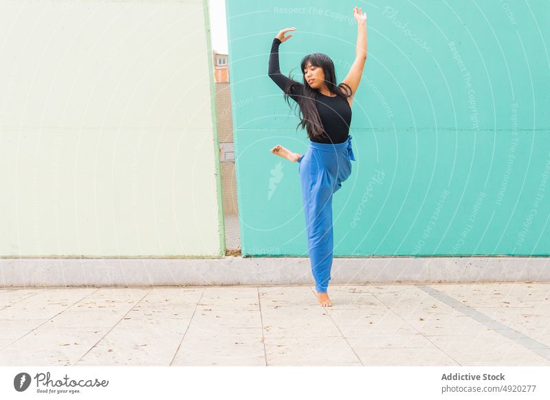 Asian woman dancing on pavement dance street grace wall arm raised urban female young asian ethnic energy talent barefoot long hair black hair practice dancer