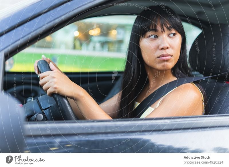 Ethnic woman driving car in city driver street summer park weekend urban steering wheel commute female young ethnic asian vehicle transport automotive dark hair