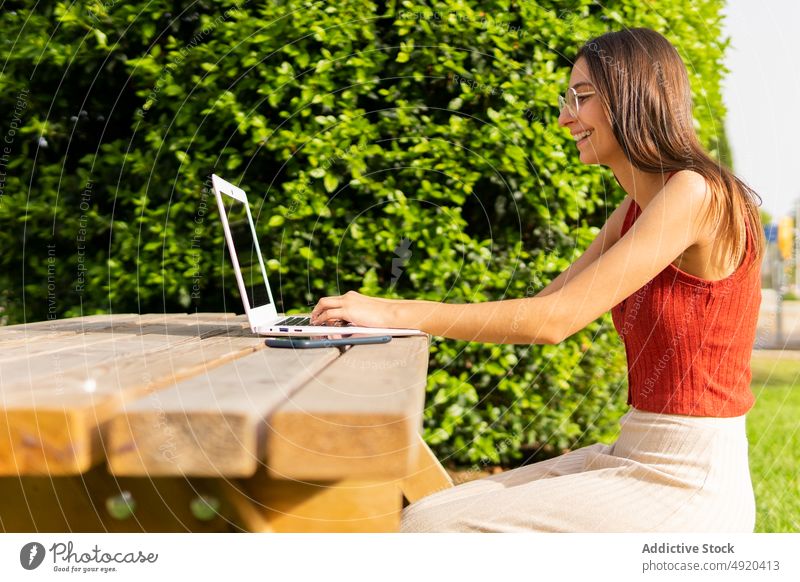 Student browsing laptop in park woman student homework study education learn online project tree knowledge smart device typing prepare diligent search