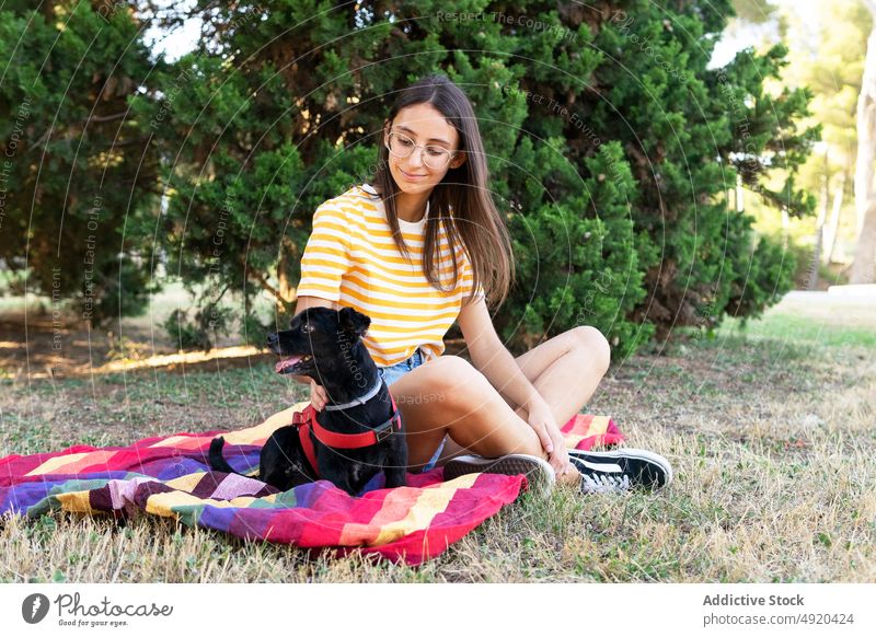 Happy young woman with dog on colorful blanket hug sit park weekend smile owner puppy love female happy pet glad companion positive optimist adorable rest