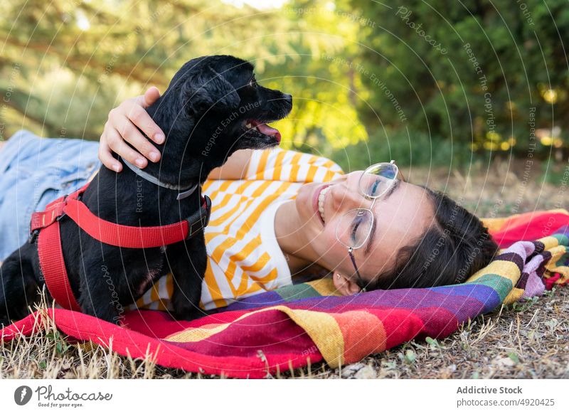Happy young woman with dog on colorful blanket hug park weekend smile owner puppy love female happy pet glad companion positive optimist adorable rest cheerful