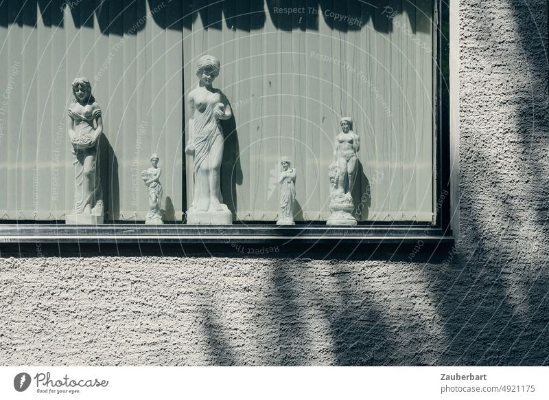Female statues made of plaster in a window in front of slats, rough plastered wall and shadow Statue feminine Gypsum Window Sun Wall (building) Plaster harsh