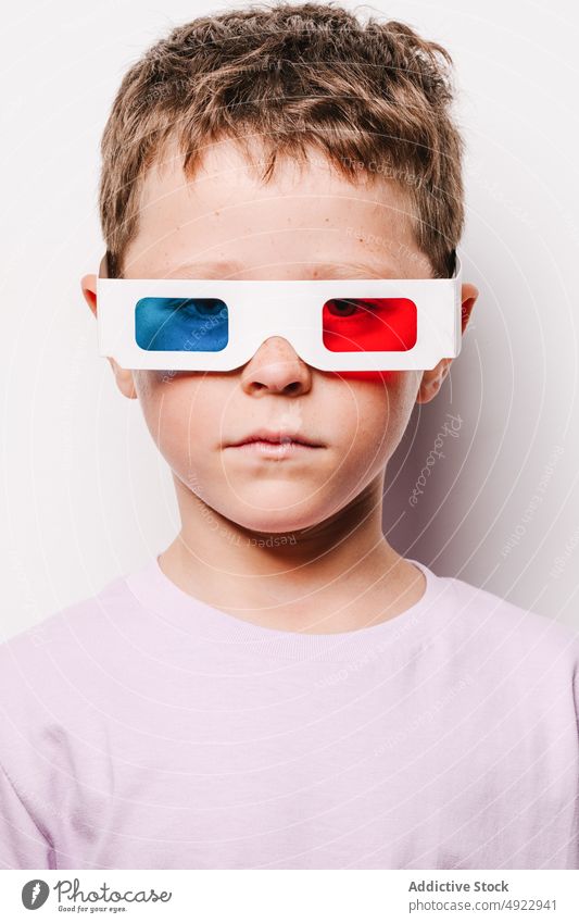 Emotionless boy with colorful 3D glasses 3d kid entertain vision amusement childhood hobby cardboard casual studio optical adorable style appearance sweet