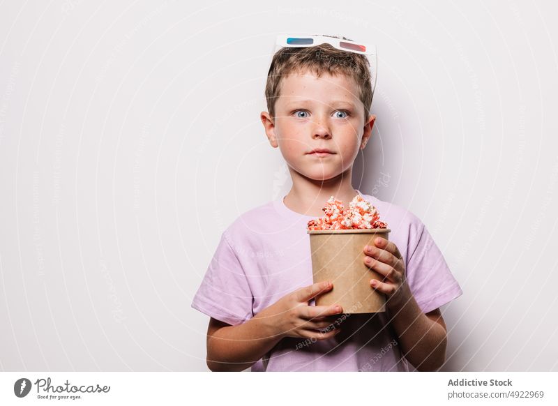 Astonished boy with 3D glasses and popcorn kid 3d snack amusement astonish movie shock treat wow light bucket stare amazed dumbfound hobby cinema food entertain