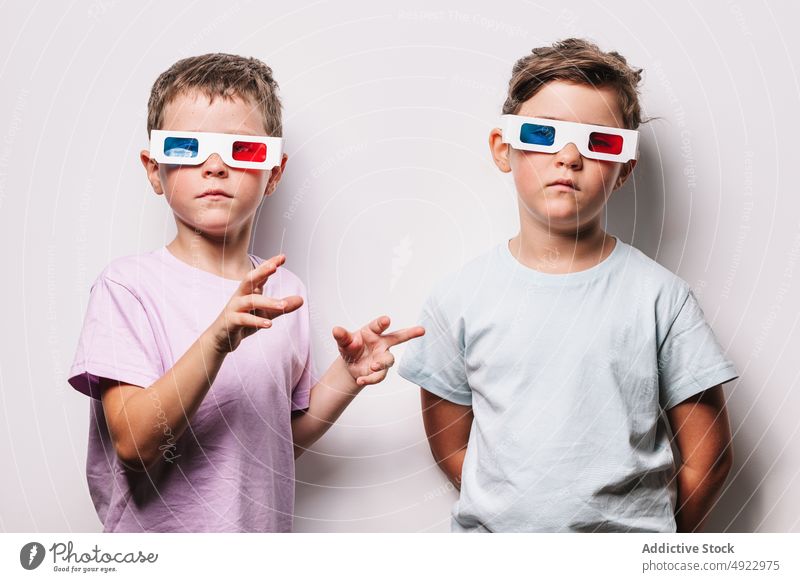 Serious children in 3D glasses 3d sibling vision serious cinema movie together calm hobby kid childhood paper boy girl casual studio optical adorable amusement