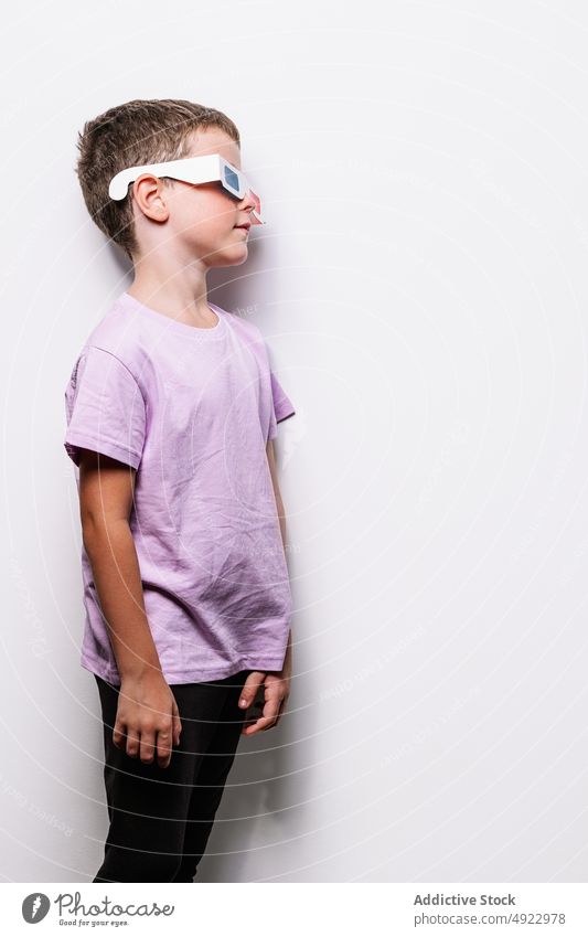Boy in 3D glasses standing near wall boy 3d child vision entertain hobby imagination amusement childhood three dimensional fantasy illusion cardboard paper