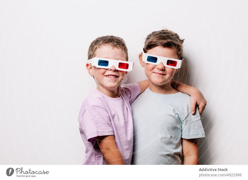 Content children in 3D glasses hugging in studio sibling 3d amusement entertain bonding having fun playful carefree cheerful embrace delight content glad
