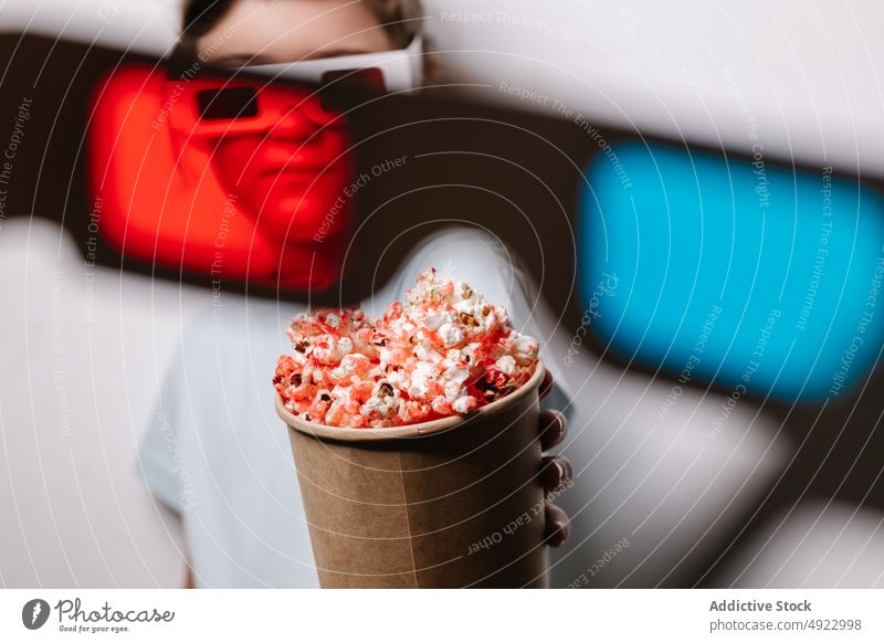 Through red lens view of girl with popcorn kid 3d glasses amusement snack entertain treat hobby glad optimist positive cinema food flavor delicious tasty