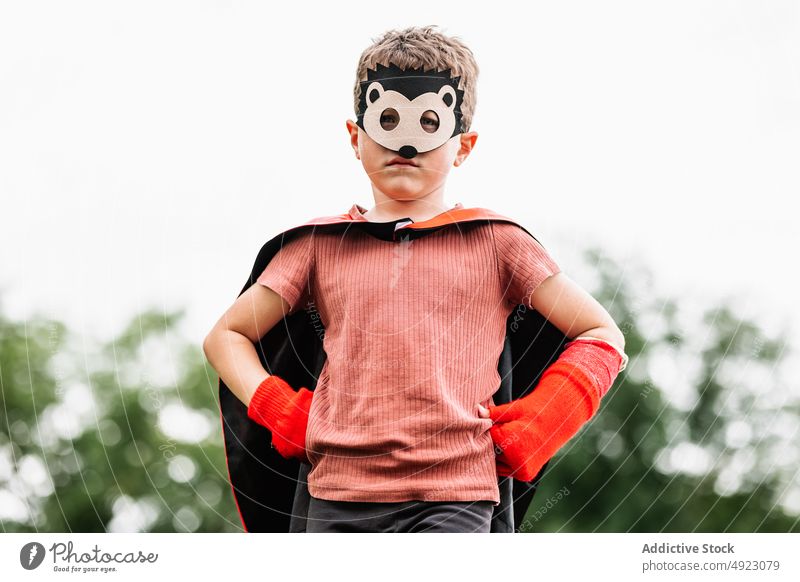 Superhero in hedgehog mask in park boy superhero play climb weekend costume pretend kneel stone block protect courage child kid cape hands on waist childhood
