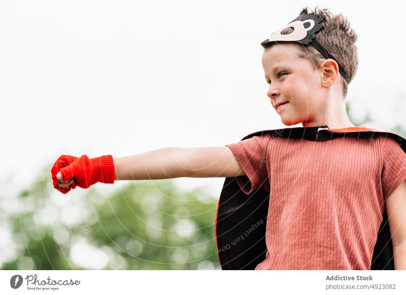 Superhero in hedgehog mask in park with outstretch arm with clenched fist boy superhero play climb weekend costume pretend kneel stone block courage child kid