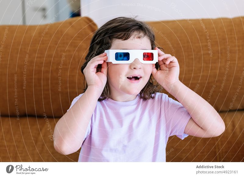 Content girl putting on 3D glasses at home 3d put on movie kid amused showtime entertain television realistic living room three dimensional free time content