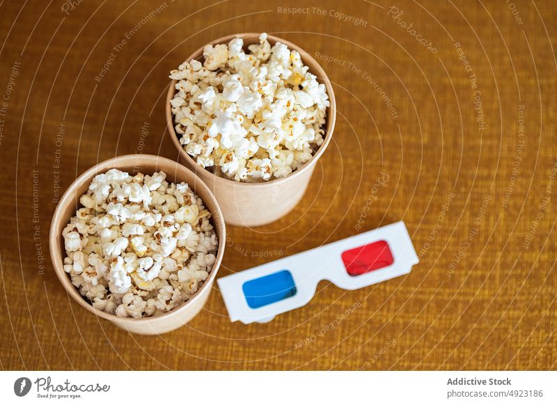 3D glasses with popcorn on couch 3d sofa snack showtime movie living room entertain food unhealthy yummy tasty bucket fast food calorie television home modern
