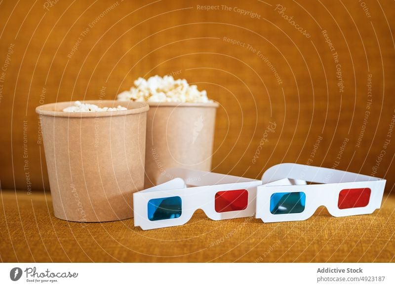 3D glasses with popcorn on couch 3d sofa snack showtime movie living room entertain food unhealthy yummy tasty bucket fast food calorie television home modern