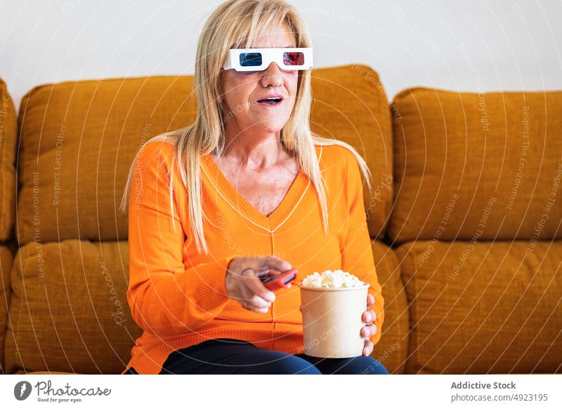 Woman in 3D glasses eating popcorn woman 3d movie watch home showtime channel controller snack television remote entertain food calorie tasty appetizing