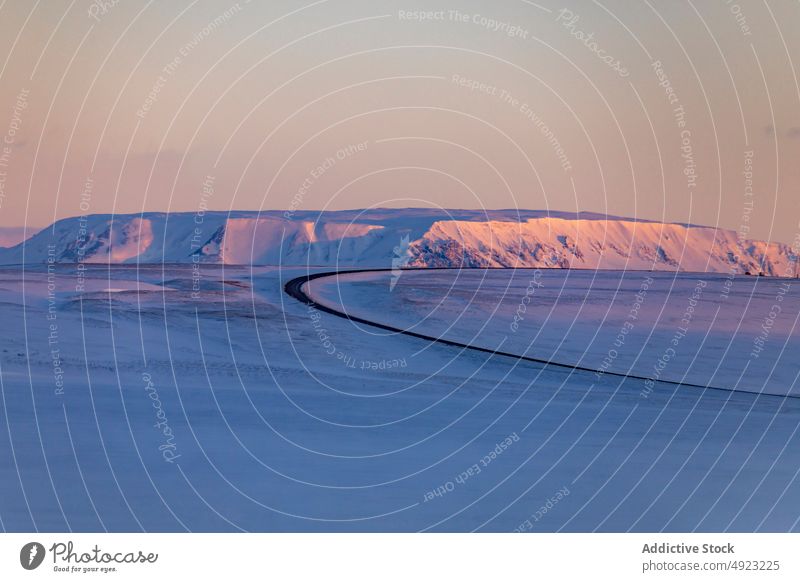 Curved road in mountains in winter curve snow roadway sunset highland empty winding valley iceland landscape twilight asphalt route scenic nature sundown