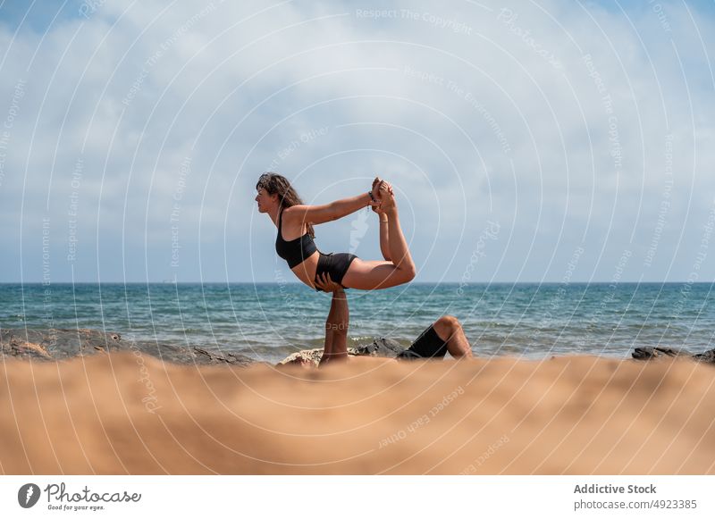 Man and woman doing acro yoga near sea waves couple beach balance together summer practice shore asana girlfriend boyfriend seaside energy session stretch