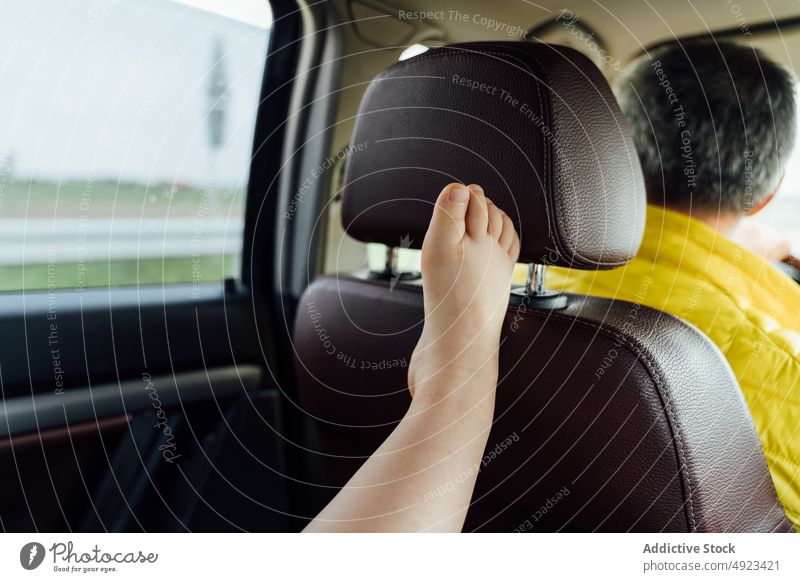 Crop anonymous child leaning raised leg on window in car leg raised road trip passenger relax vehicle transport rain cloudy kid barefoot countryside weekend