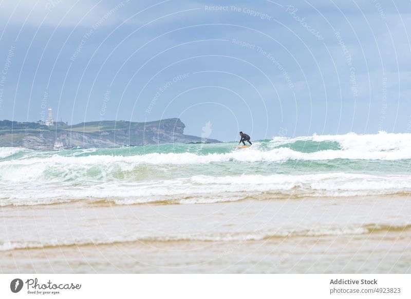 Anonymous man riding wave on surfboard in ocean surfer surfing extreme ride activity practice hobby sport male wetsuit sporty adrenalin active balance energy