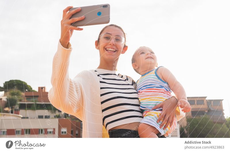 Young mother taking selfie with son on street smartphone smile carry happy weekend together woman boy young love house cheerful device mobile mom glad child