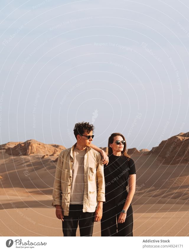 Traveling couple standing in desert holding hands trip love vacation traveler holiday together relationship scenic boyfriend girlfriend young style sunglasses