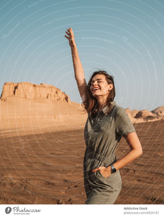 Happy woman standing in desert nature trip travel adventure journey tourist rock enjoy pastime arm raised happy eyes closed cheerful positive optimist formation