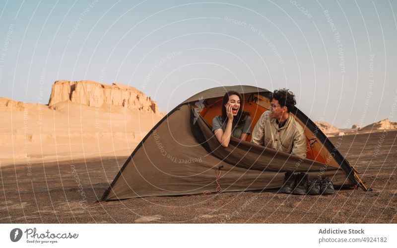 Happy couple in tent in desert campsite rest nature trip adventure rock bonding relationship positive love enjoy smile together formation cheerful glad