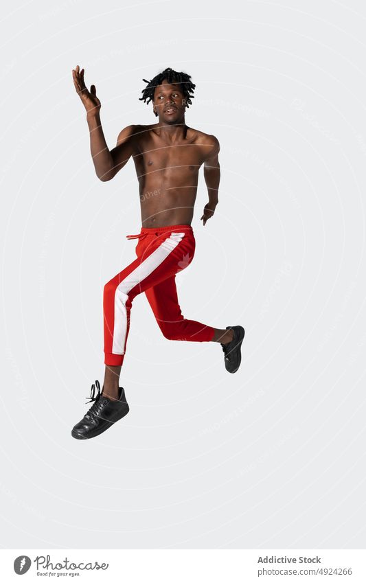 Shirtless black sportsman leaping up jump energy training power mid air exercise activity strength male young african american ethnic naked torso effort