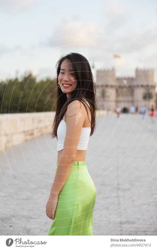 Beautiful young Asian woman walking the street of historic European town. Female tourist from China traveling in Europe, smiling. Exchange student. beautiful