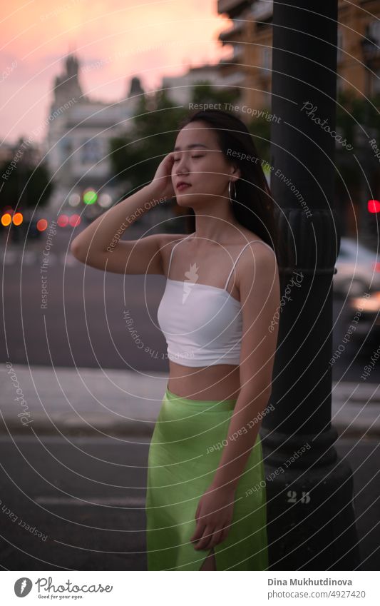 Beautiful young Asian woman walking the street of modern city at sunset. Female tourist from China traveling in Europe. Fashion and style concept. beautiful