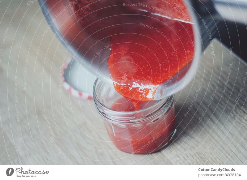 Homemade jam being poured in a jar homemade fruit healthy pouring preparation strawberry healthy lifestyle domestic kitchen closeup tasty delicious refreshing