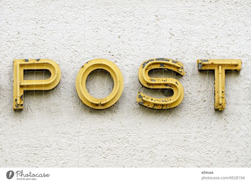old yellow illuminated letters POST on a house wall / post office Post office Mail Neon sign Illuminated advertising letter neon advertisement Old broken