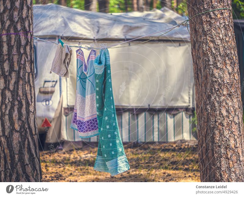 Towels on clothesline between two trees on the campsite. In the background a caravan with awning. Longing camping travel Wanderlust Vehicle voyage Old Adventure