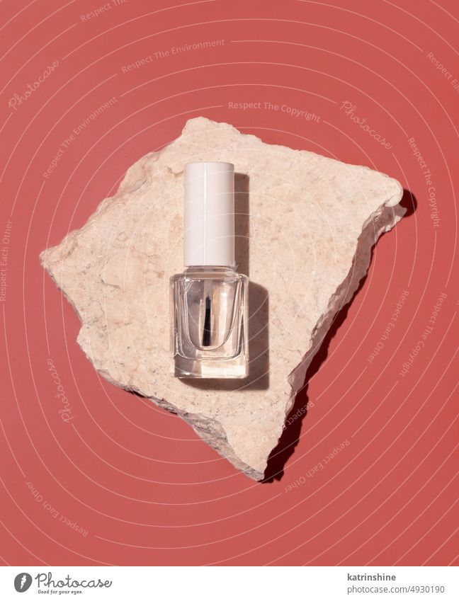 Glass Bottle with Brush Cap near travertine stones on pink top view. Mockup bottle cosmetics nail mockup Hard shadow Refillable clear glass transparent white