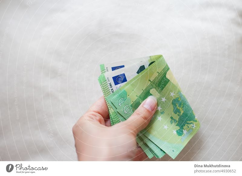 Hand holding a bunch of green 100 euro banknotes closeup. Inflation in European Union concept. Money on white surface isolated. Pile of one hundred euro notes. Cash payments concept.