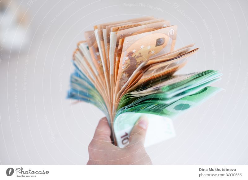 Hand holding a bunch of euro banknotes closeup. Inflation in European Union concept. Money on white surface isolated. Pile of one hundred, fifty and twenty euro notes. Thousands of euro cash payments concept. Deposit money, loan, mortgage concepts.