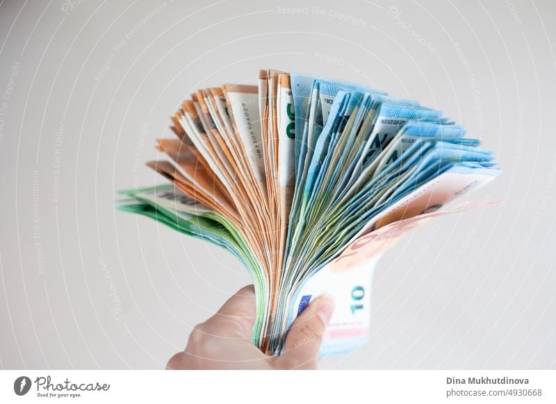 Hand holding a bunch of euro banknotes closeup. Inflation in European Union concept. Money on white surface isolated. Pile of one hundred euro notes. Cash payments concept. Deposit money, loan, mortgage concepts.