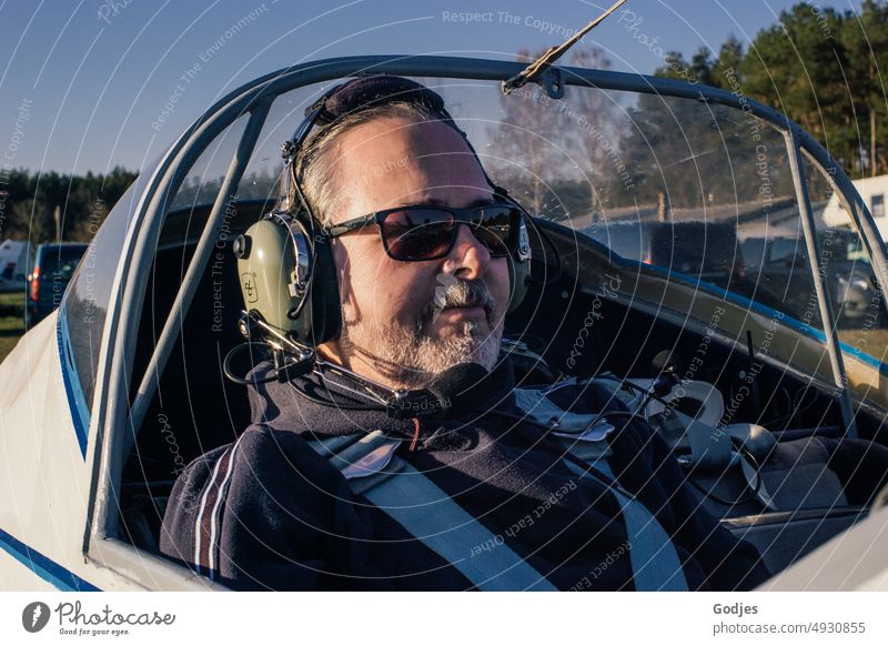 Man sits in plane with headset on head Flying Two-seater Aviation Airplane portrait Airplane takeoff Vacation & Travel Airplane landing Sky Colour photo Airport