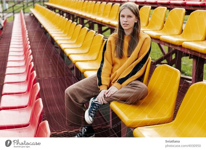 Portrait of a charming girl sitting on the school bleachers during a break teen stadium student studying university high school resting near young female youth