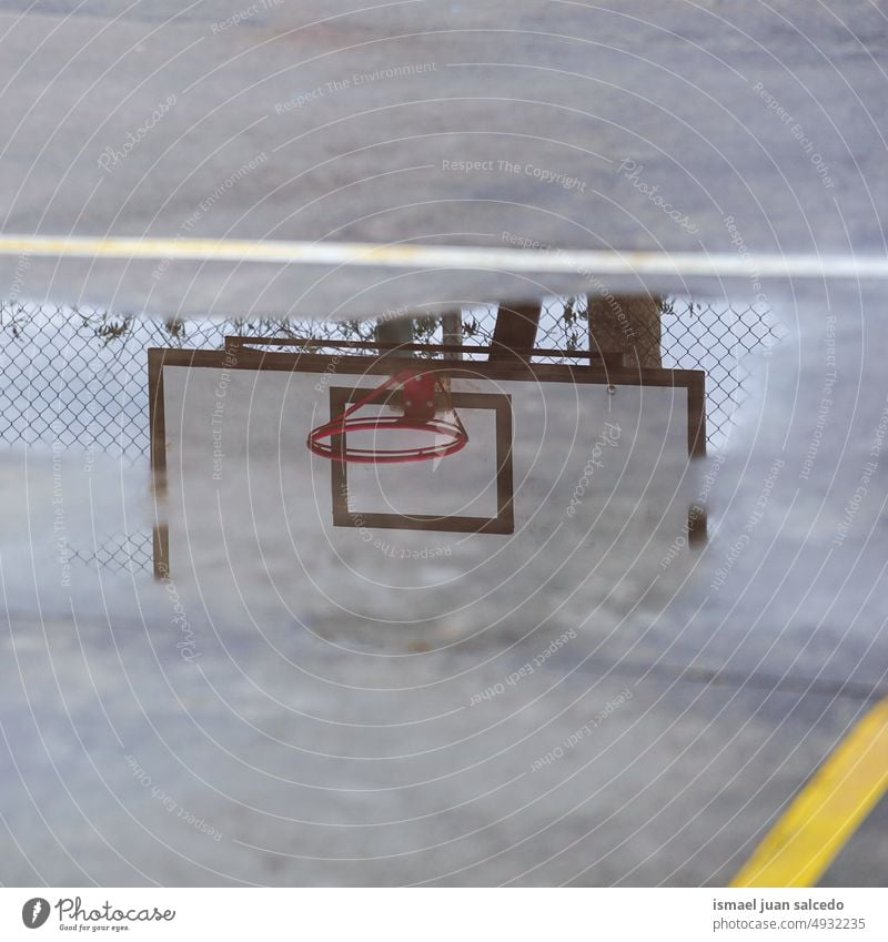 street basket hoop reflected in a puddle basketball sports equipment reflection silhouette water rain rainy ground court field floor play playing park