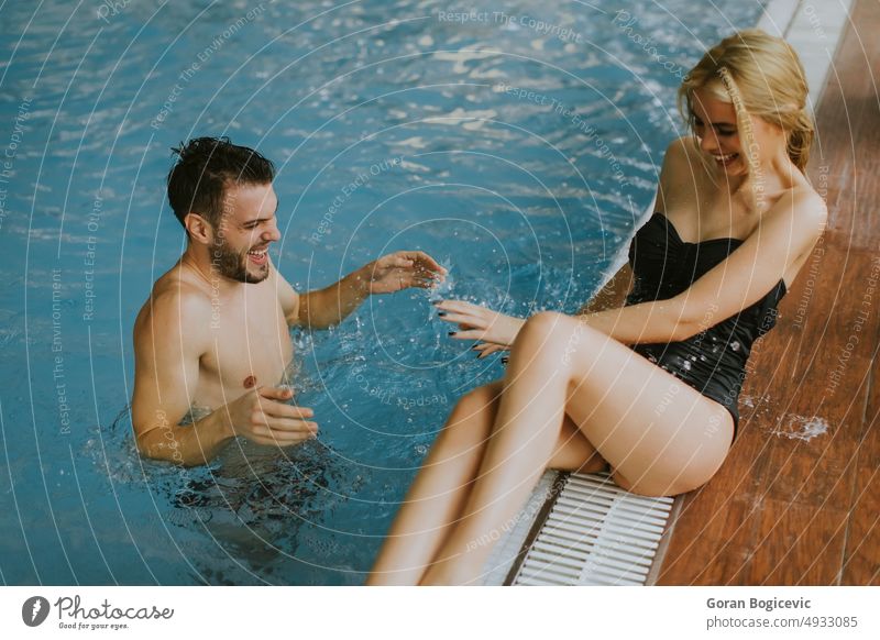 Young couple relaxing on the poolside of interior swimming pool woman smile water young happy wellness indoor adult caucasian enjoy bikini swimsuit female